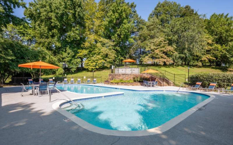 a swimming pool with a fence and trees in the background