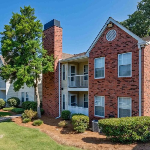 a brick building with a lawn and trees in front of it